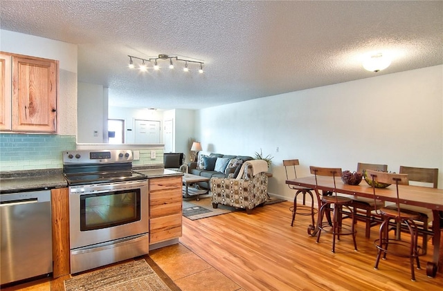 kitchen with dark countertops, a textured ceiling, appliances with stainless steel finishes, and open floor plan
