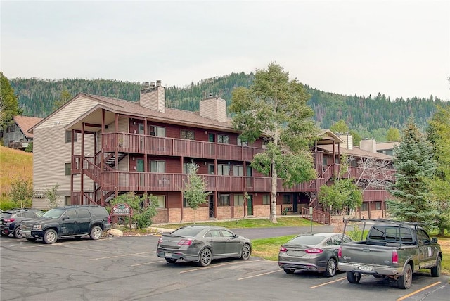 view of property with a forest view, stairs, and uncovered parking