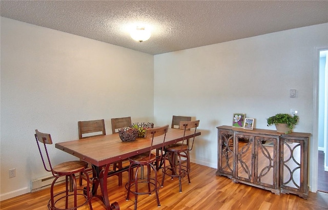dining room featuring baseboards, baseboard heating, wood finished floors, and a textured ceiling