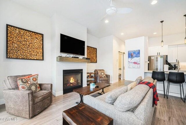 78311 US Highway 40 Unit 6, Winter Park, CO 80482 - living area with light wood finished floors, baseboards, a warm lit fireplace, and ceiling fan