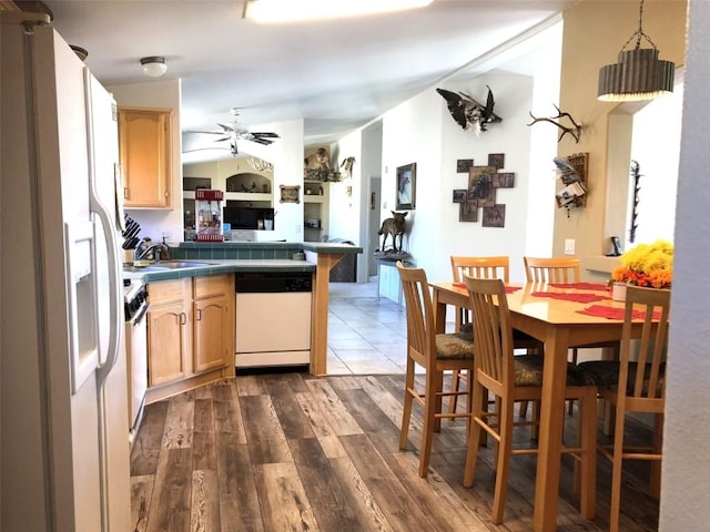 kitchen featuring dark wood finished floors, a sink, white appliances, a peninsula, and ceiling fan