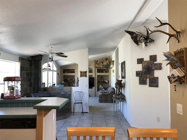 kitchen featuring tile patterned flooring, dishwashing machine, a ceiling fan, tile countertops, and open floor plan