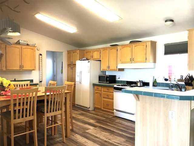 kitchen with vaulted ceiling, tile countertops, white appliances, under cabinet range hood, and dark wood-style floors