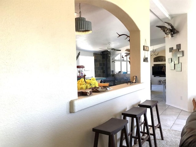interior space featuring arched walkways, ceiling fan, and light tile patterned flooring