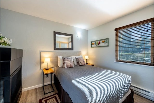 bedroom with baseboards, wood finished floors, and a baseboard radiator
