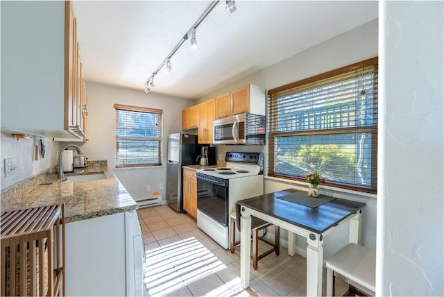 kitchen with stainless steel appliances, light tile patterned floors, a baseboard heating unit, a sink, and stone counters