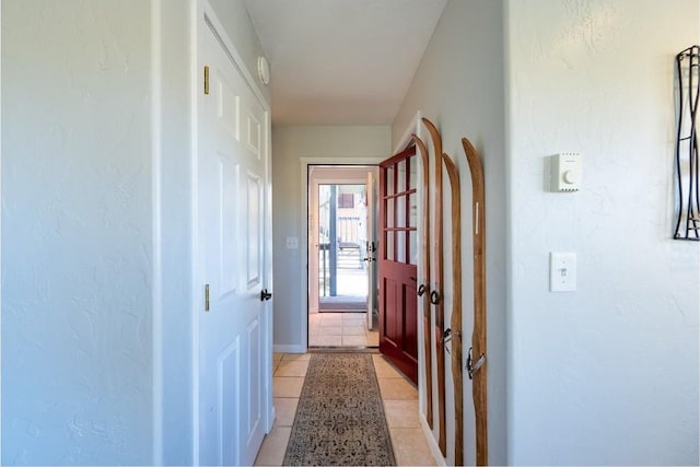 corridor featuring baseboards and light tile patterned floors