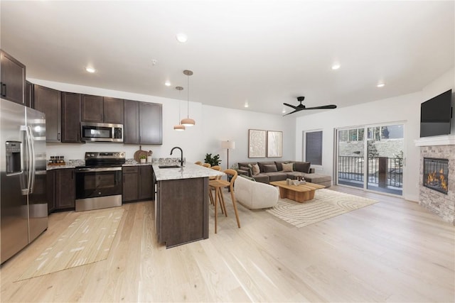 35 Argentine Ct Unit 303, Keystone, CO 80435 - kitchen with stainless steel appliances, a peninsula, open floor plan, dark brown cabinetry, and light wood-style floors