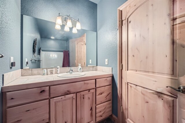91795 Ryan Gulch Rd, Silverthorne, CO 80498 - full bathroom featuring curtained shower, a textured wall, vanity, and an inviting chandelier