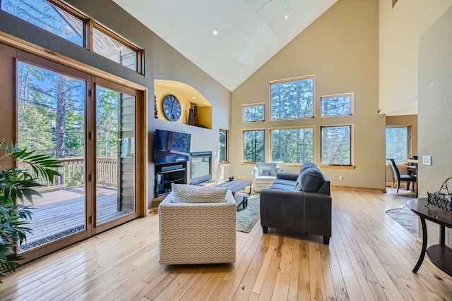 living area featuring light wood finished floors, baseboards, and high vaulted ceiling