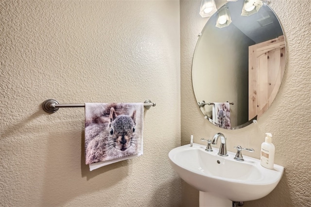 bathroom featuring a textured wall and a sink