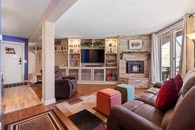 living area with a stone fireplace and wood finished floors
