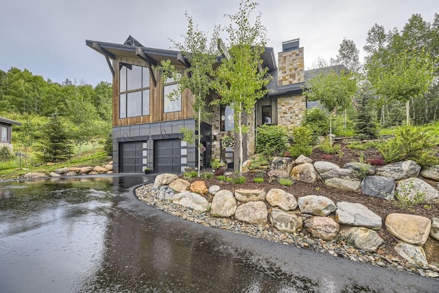 313 Raven Golf Ln, Silverthorne, CO 80498 - contemporary home featuring a garage, driveway, board and batten siding, a chimney, and stone siding