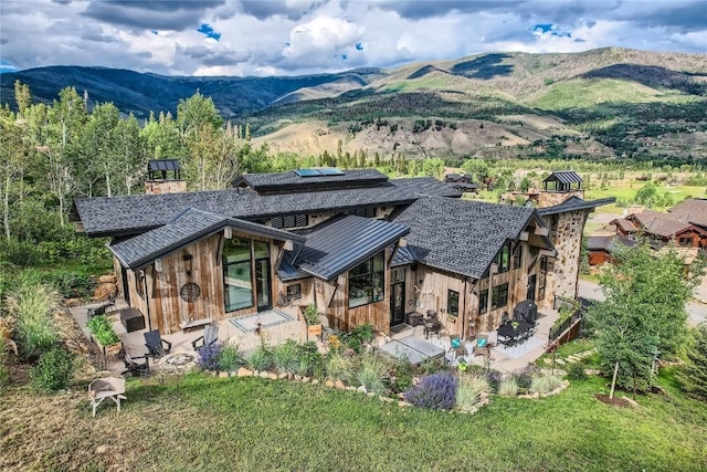 313 Raven Golf Ln, Silverthorne, CO 80498 - back of house featuring roof mounted solar panels, a patio, a mountain view, a shingled roof, and a standing seam roof