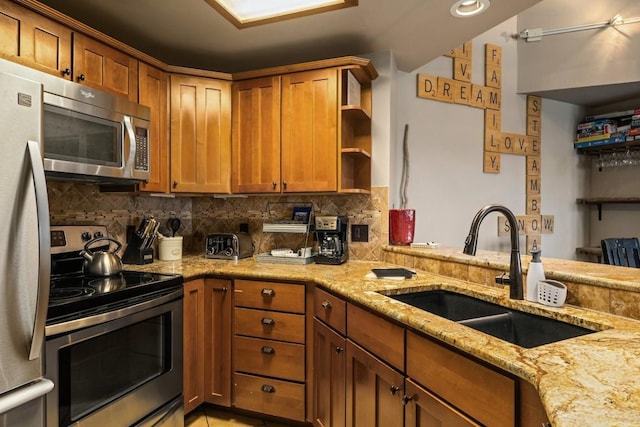 2800 Village Dr Unit 1302, Steamboat Springs, CO 80487 - kitchen with appliances with stainless steel finishes, a sink, open shelves, brown cabinetry, and light stone countertops