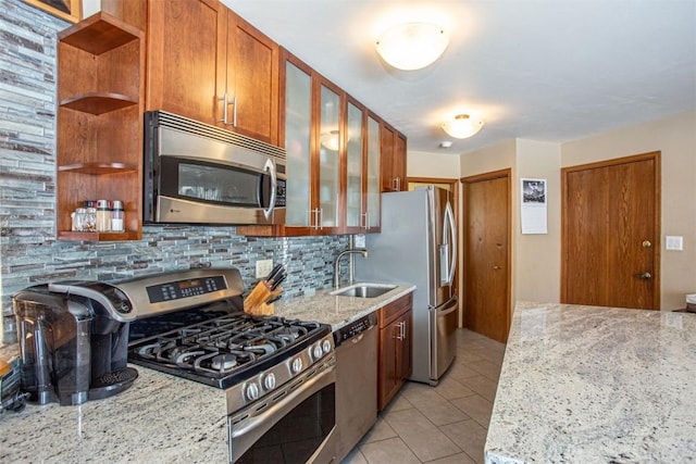 kitchen with open shelves, a sink, backsplash, appliances with stainless steel finishes, and light stone countertops