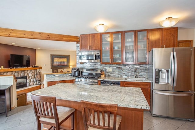kitchen with tasteful backsplash, a sink, brown cabinetry, light tile patterned floors, and appliances with stainless steel finishes
