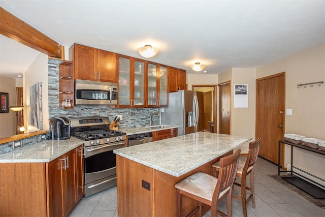 kitchen featuring a sink, decorative backsplash, appliances with stainless steel finishes, a breakfast bar, and light tile patterned floors