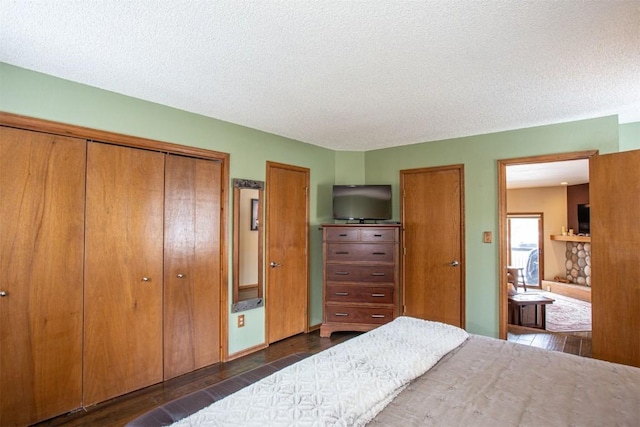 bedroom with ensuite bath, dark wood finished floors, and a textured ceiling