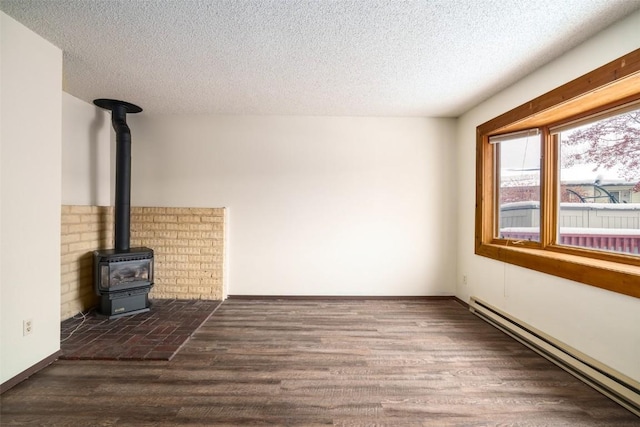 13 Sequoia Ct Unit 13, Steamboat Springs, CO 80487 - unfurnished living room with wood finished floors, a baseboard radiator, a wood stove, and a textured ceiling
