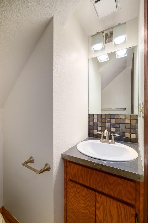 13 Sequoia Ct Unit 13, Steamboat Springs, CO 80487 - bathroom featuring vaulted ceiling, vanity, a textured ceiling, and tasteful backsplash