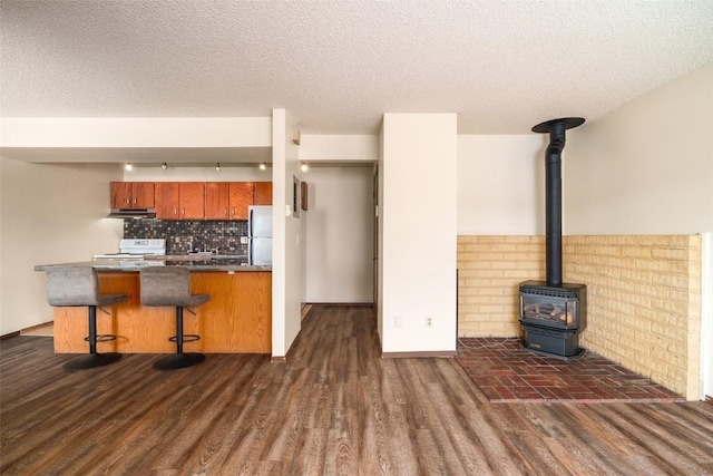 13 Sequoia Ct Unit 13, Steamboat Springs, CO 80487 - kitchen with brown cabinets, dark wood finished floors, a wood stove, freestanding refrigerator, and a breakfast bar area