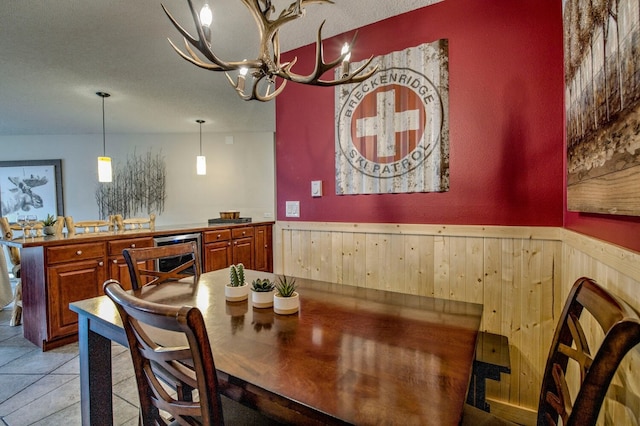 dining space featuring a wainscoted wall, wood walls, and a notable chandelier