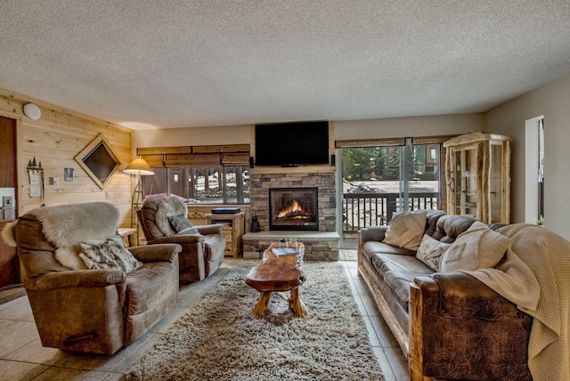 living room featuring a textured ceiling, wood walls, a fireplace, and tile patterned flooring