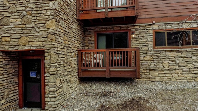 doorway to property featuring stone siding and a balcony