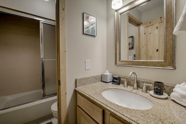 bathroom with vanity, toilet, and combined bath / shower with glass door