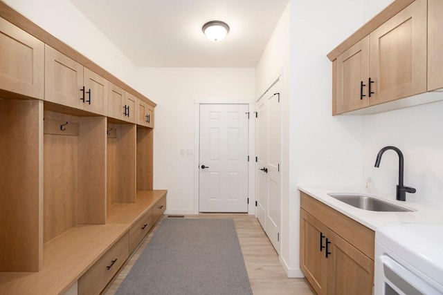 mudroom with light wood-type flooring and a sink