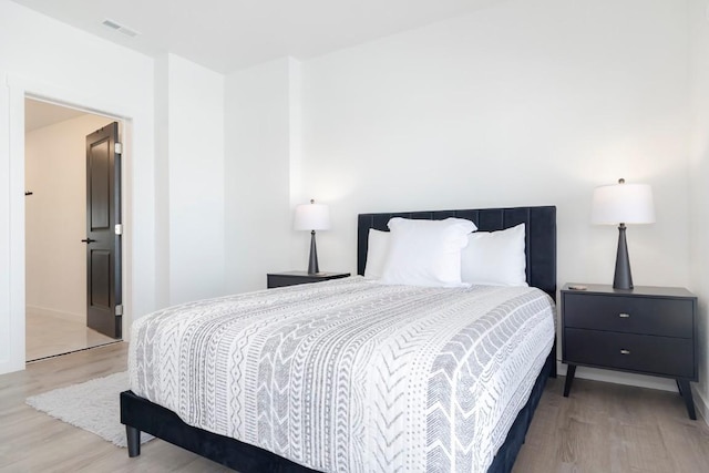 bedroom featuring baseboards, light wood-style floors, and visible vents