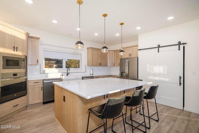 kitchen featuring light wood-style flooring, a sink, appliances with stainless steel finishes, and a kitchen island