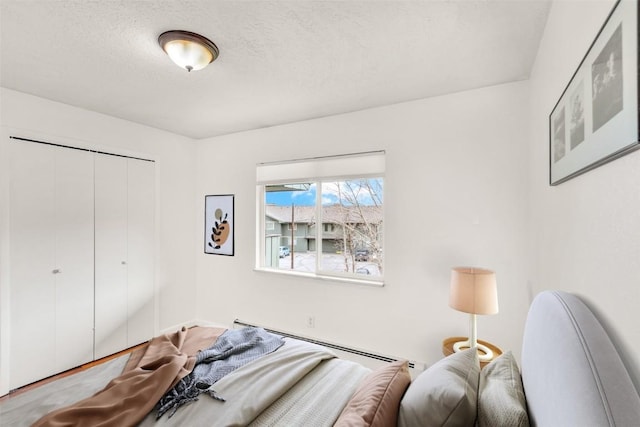 bedroom featuring a closet, a textured ceiling, and baseboard heating