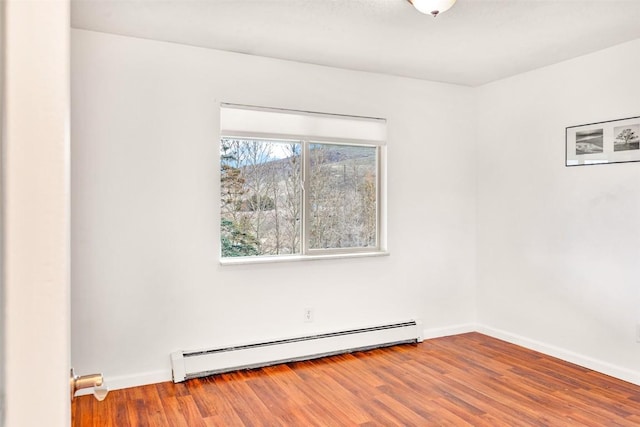 empty room with baseboards, baseboard heating, and wood finished floors