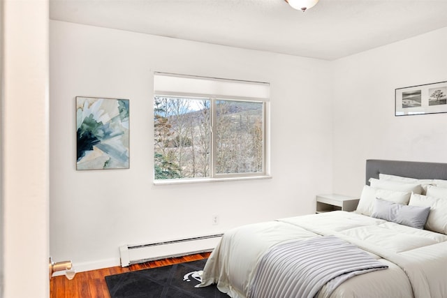 bedroom with baseboards, baseboard heating, and wood finished floors
