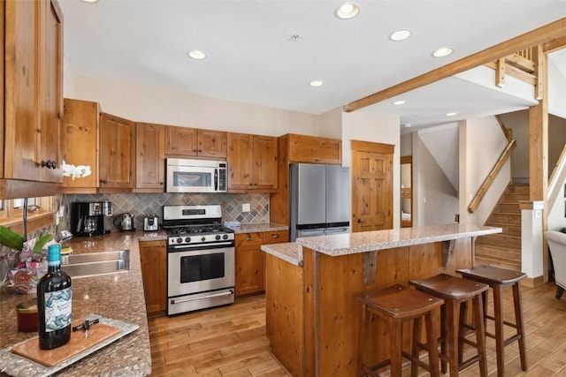 129 Tip Top Trl Unit 6543, Keystone, CO 80435 - kitchen featuring a center island, light wood-type flooring, backsplash, brown cabinetry, and appliances with stainless steel finishes