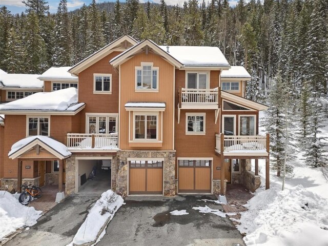 129 Tip Top Trl Unit 6543, Keystone, CO 80435 - view of front of home with driveway, stone siding, an attached garage, a balcony, and a forest view