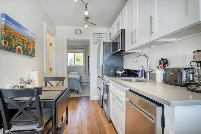 3295 Apres Ski Way Unit B10, Steamboat Springs, CO 80487 - kitchen with appliances with stainless steel finishes, white cabinets, light wood-style floors, and light countertops