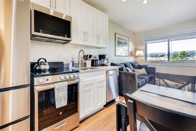 3295 Apres Ski Way Unit B10, Steamboat Springs, CO 80487 - kitchen featuring stainless steel appliances, white cabinetry, light wood finished floors, light countertops, and open floor plan