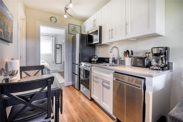 3295 Apres Ski Way Unit B10, Steamboat Springs, CO 80487 - kitchen with appliances with stainless steel finishes, white cabinetry, light wood-style flooring, a baseboard heating unit, and light countertops