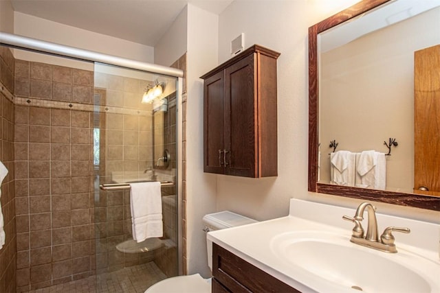 full bathroom with vanity, a shower stall, and toilet