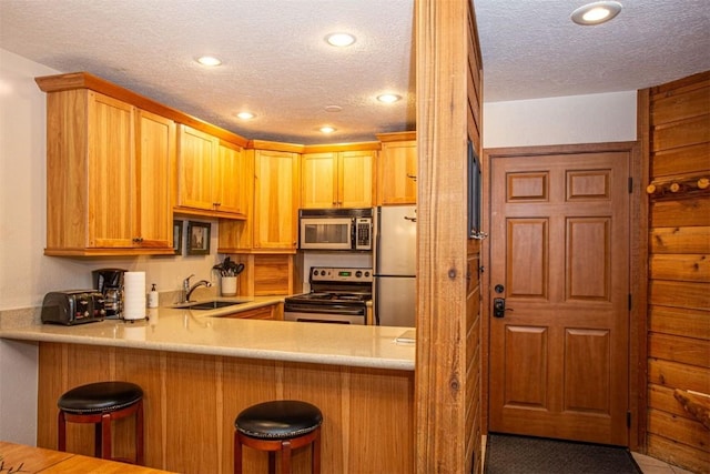 kitchen featuring appliances with stainless steel finishes, a sink, a textured ceiling, and recessed lighting