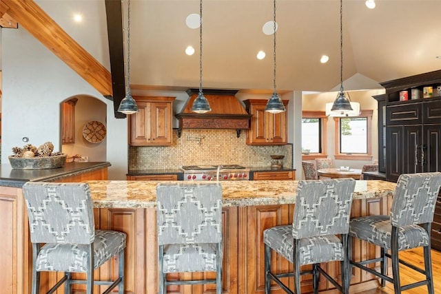174 Sage Dr, Breckenridge, CO 80424 - kitchen with custom exhaust hood, a kitchen breakfast bar, tasteful backsplash, light stone counters, and vaulted ceiling