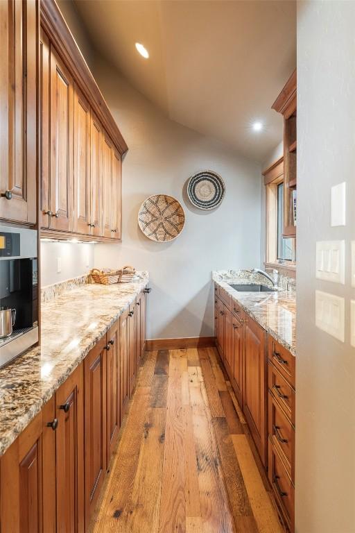 174 Sage Dr, Breckenridge, CO 80424 - kitchen with light stone counters, a sink, light wood finished floors, baseboards, and lofted ceiling