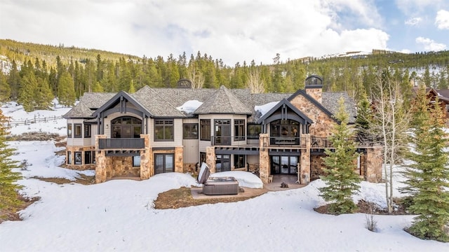 174 Sage Dr, Breckenridge, CO 80424 - snow covered back of property featuring a wooded view, a chimney, a balcony, and stone siding