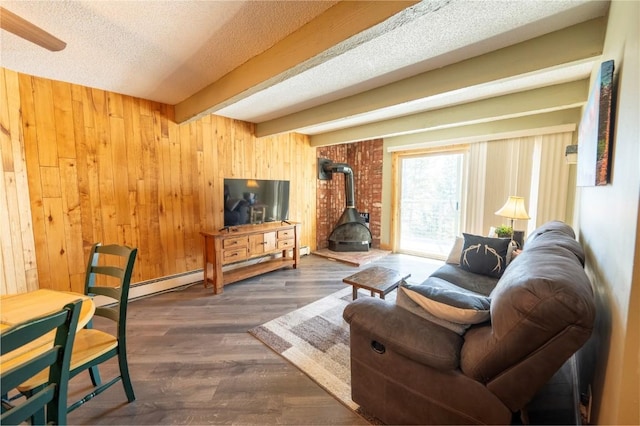 living area featuring wooden walls, a wood stove, beamed ceiling, a textured ceiling, and baseboard heating