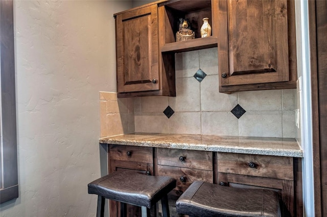 107 Ski Watch Rd Unit 432, Breckenridge, CO 80424 - kitchen featuring a textured wall, tasteful backsplash, light stone counters, open shelves, and dark brown cabinetry