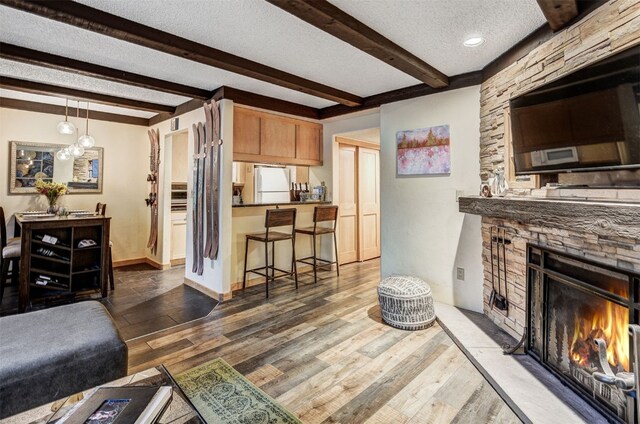 311 S High St Unit 108, Breckenridge, CO 80424 - living area featuring beam ceiling, wood finished floors, a textured ceiling, a fireplace, and baseboards