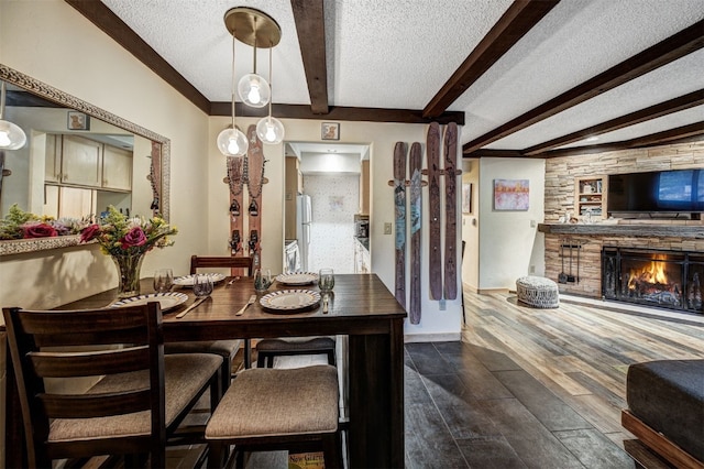 311 S High St Unit 108, Breckenridge, CO 80424 - dining room with a textured ceiling, beam ceiling, dark wood-type flooring, and a stone fireplace
